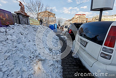 Vladivostok, Russia, 2017 - Dirty street in Vladivostok. Cars are parked in front of large muddy snow drifts on the streets of Editorial Stock Photo