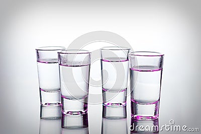 Vodka shots lighted with pink light filled with alcohol on glass bar table Stock Photo