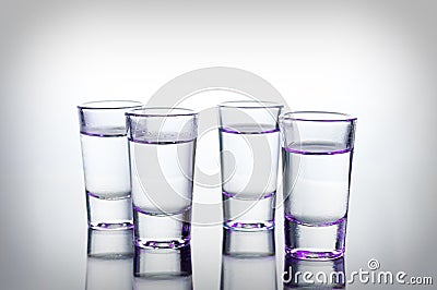 Vodka shots lighted with purple light filled with alcohol on glass bar table Stock Photo