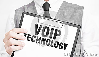VOIP TECHNOLOGY inscription on a notebook in the hands of a businessman on a gray background, a man points with a finger to the Stock Photo