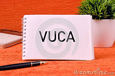 Volatility Uncertainty Complexity Ambiguity. VUCA text on a blank notepad page on an orange back Stock Photo