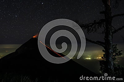 Volcano fuego erupting in nightsky with stars and a tree in the forground Stock Photo