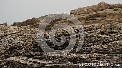 Volcanogenic rock slabs on the seashore. Natural rocky breakwater at seashore Stock Photo