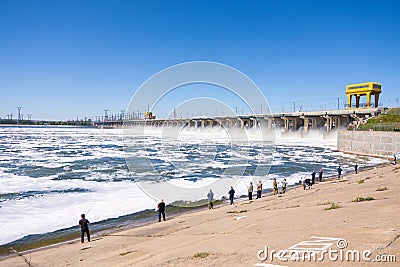 Volgograd. Russia - 16 April 2017. The dam of the Volga hydroelectric water discharge and fishermen at the dam Editorial Stock Photo