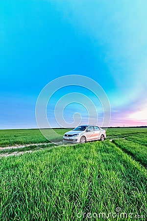 Volkswagen Polo Vento on a rural road in a wheat field in the ev Editorial Stock Photo