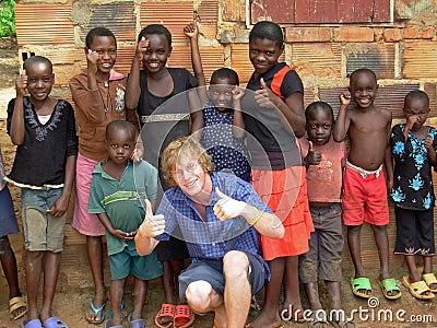 Volunteer aid relief worker having fun teaching African children thumbs up Editorial Stock Photo