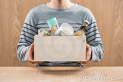 Volunteer with donation box with food stuffs on wooden background Stock Photo