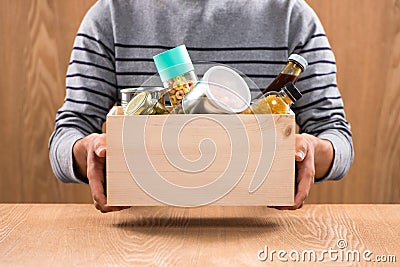 Volunteer with donation box with foodstuffs on wooden background Stock Photo