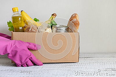 Volunteer in gloves contactless delivery food. Box with stocks, vegetables, cereals, bread fruits Stock Photo