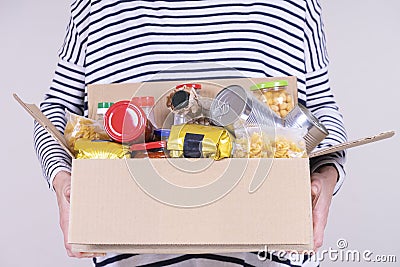 Volunteer hands holding food donations box with grocery products on white desk Stock Photo