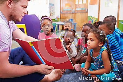 Volunteer teacher reading to a class of preschool kids Stock Photo
