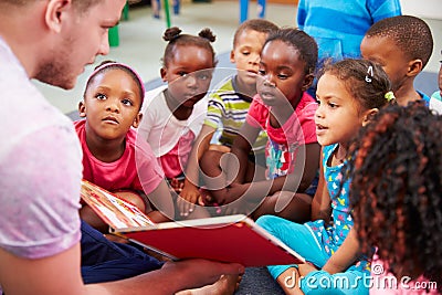 Volunteer teacher reading to a class of preschool kids Stock Photo