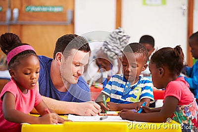 Volunteer teacher sitting with preschool kids in a classroom Stock Photo