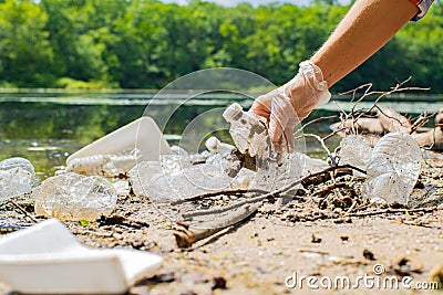 Volunteers cleaning garbage near river. Women picking up a bottle plastic in the lake, pollution and environment Stock Photo