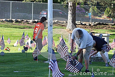 Volunteers placing an American Flag on the grave of a Military Veteran for Memorial Day Editorial Stock Photo