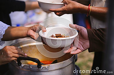 Volunteers provide food for beggars : Concepts Feeding and help : The hands of the rich give food to the hands of the poor Stock Photo