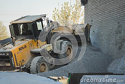 Voronezh region, Russia, april, 25 2019. Tractor loads crushed stone in the production of concrete. Yellow tractor loader running Editorial Stock Photo