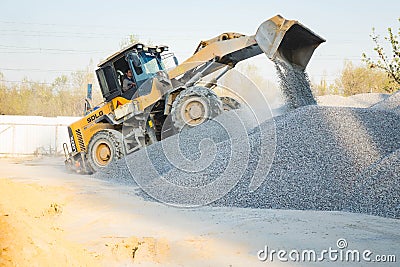 Voronezh region, Russia, april, 25 2019. Tractor loads crushed stone in the production of concrete. Yellow tractor loader running Editorial Stock Photo