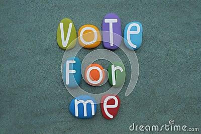 Vote for me, social slogan composed with multi colored stone letters over green sand Stock Photo