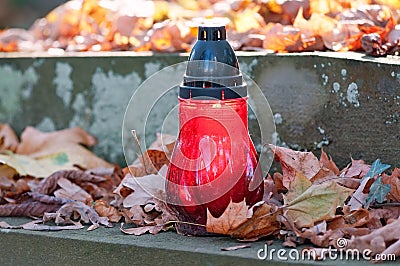 Votive candle at the grave with autumn leaves Stock Photo