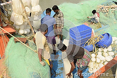 Voyage preparation made by fishing trawler crew by repairing nets, store ice blocks at Frezargunj, West Bengal, India Editorial Stock Photo