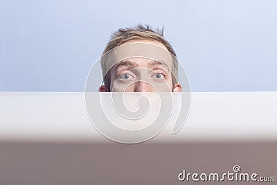 Voyeurism. Young man look out from behind the table. Stock Photo