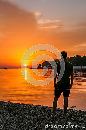 Vrsar - A young man enjoying the sunset by the beach Stock Photo