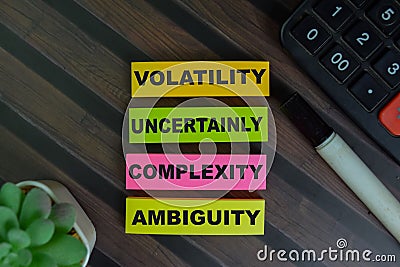 VUCA - Volatility Uncertainly Complexity Ambiguity write on sticky notes isolated on Wooden Table Stock Photo