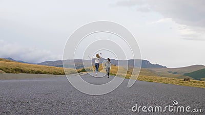 Vue arrière d'encourager de jeunes amis féminins courant sur une route de montagne exprimant la joie et la liberté en leurs vacan clips vidéos Vue arrière d'encourager de jeunes amis féminins courant sur une route de montagne exprimant la joie et la liberté en leurs vacan clips vidéos