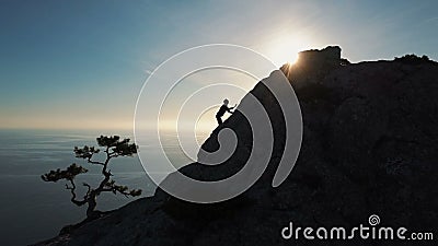 Vue aérienne épique d'une silhouette d'une jeune femme grimpant au sommet d'une montagne contre la mer au coucher du soleil Lady banque de vidéos Vue aérienne épique d'une silhouette d'une jeune femme grimpant au sommet d'une montagne contre la mer au coucher du soleil Lady banque de vidéos