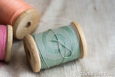 Vintage wooden thread spools on linen cloth, pastel colors, closeup, styled image Stock Photo