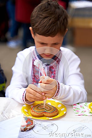 Vyshyvanka day in Ukraine. Kid painting Ukrainian flag in shape of heart on gingerbread Editorial Stock Photo