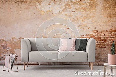 Wabi sabi living room interior with old shabby wall and trendy new couch with pastel pink and black pillows, real photo Stock Photo