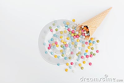 Waffle cone and heap colorful candy on white background from above. Flat lay style. Stock Photo