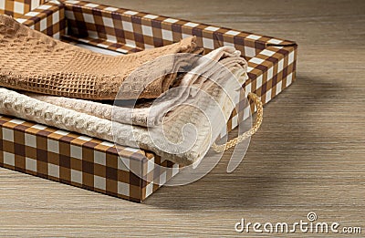 Waffle towels are stacked in a checkered gift box on a wooden table, top view, Domestic Life Stock Photo
