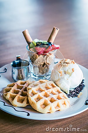 Waffles dusted with icing sugar and iceream and fruit on the side Stock Photo