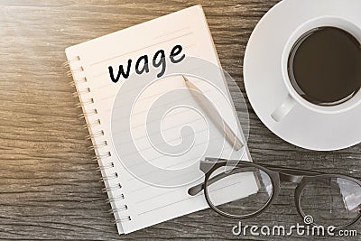 Wage word on notebook with glasses, pencil and coffee cup on woo Stock Photo