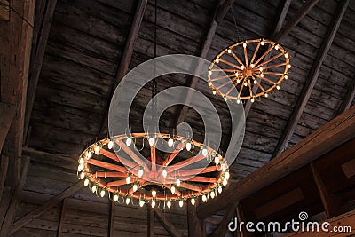 Wagon wheels hung from the ceiling of a barn with lights for a traditional old-fashioned wedding celebration Stock Photo