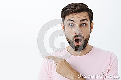 Wais-up shot of amazed and curious charming caucasian man with dark sick beard opening mouth from amazement and Stock Photo