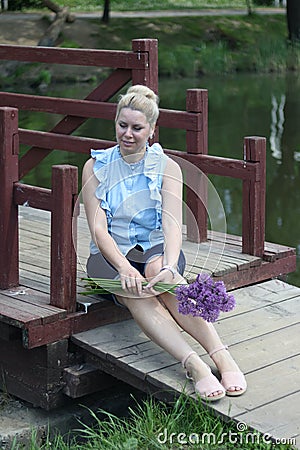 A waist portrait of a woman with a bouquet of wildflowers. Looks into the camera Stock Photo