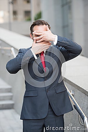 Waist up of entrepreneur hiding his face behind hands Stock Photo