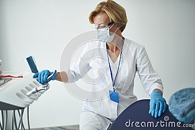 Waist up of an experienced stomatologist using modern equipment Stock Photo