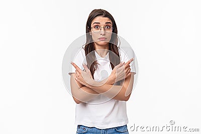 Waist-up of indecisive, clueless good-looking caucasian female in glasses, cant decide, pointing fingers sideways left Stock Photo