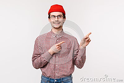 Waist-up portrait of curious excite geeky adult man in red beanie, checked shirt, pointing and looking upper right Stock Photo