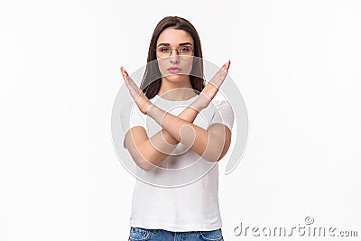 Waist-up portrait of determined, serious-looking young female activist, saying no to women opression, show cross sign in Stock Photo