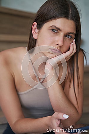 Low-spirited young woman with cellphone staring ahead Stock Photo