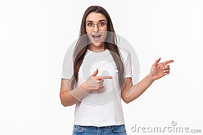 Waist-up portrait of excited, enthusiastic brunette 25s woman in t-shirt, jeans, pointing fingers right and look Stock Photo