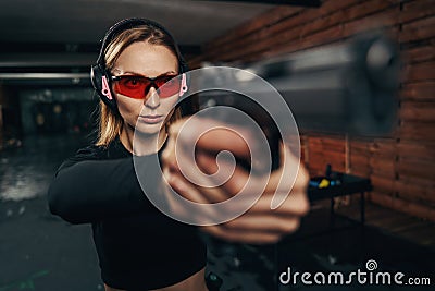 Focused beautiful shooter in earmuffs shooting a handgun Stock Photo