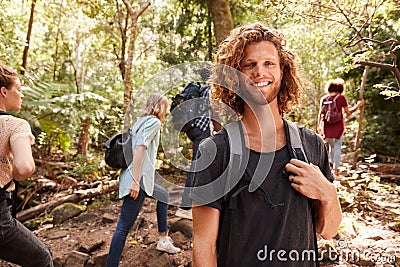 Waist up portrait of smiling millennial white man hiking in a forest with friends, close up Stock Photo