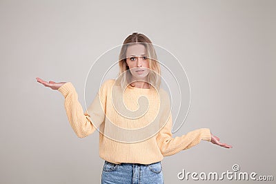 Waist-up portrait of young blonde woman with confused emotion, shrugs shoulders as she doesnt know the answer, being clueless and Stock Photo